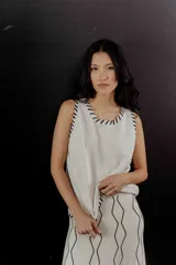 Chaleco de tejido color crudo con pespuntes negros en cuello y sisas.