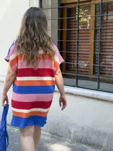 Vestido corto tejido a rayas horizontales en tonos crudo, naranja, rojo, rosa, azul y blanco.