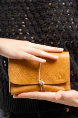 Billetera tipo sobre de cuero negro con cierre de elástico, separaciones internas y bolsillo con cierre para monedas.