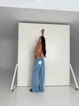 Pantalón de jean celeste con apliques de estrellas blancas en la parte trasera.