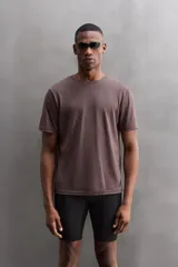 Camiseta color crema de corte relaxed fit, cuello redondo y manga corta. Tiene un texto estampado en el frente y un logo estampado en el ruedo.