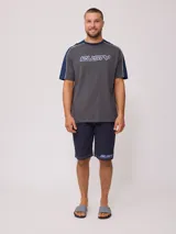 Remera de hombre azul marino con mangas y cuello amarillo, y logo de la marca Rusty estampado en el pecho.