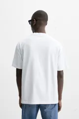 Camiseta blanca de algodón compacto, corte relaxed fit, cuello redondo y mangas cortas.
