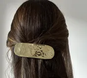 Conjunto de accesorios de metal dorado con diseños abstractos y geométricos, que incluye aros, collares y un broche, presentados en un estuche de cuero.