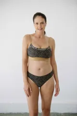 Bombacha de bikini tiro medio, corte less, color negro con estampado de puntos blancos.