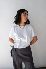 Falda gris con finas rayas verticales blancas, de corte mini y diseño cruzado con lazo lateral.