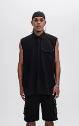 Camisa negra sin mangas de calce oversize con doble bolsillo y detalle de remaches en el frente, confeccionada en tejido twill de alta calidad.