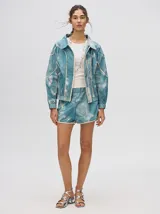 Short biker ajustado de lycra con estampado abstracto y difuminado en tonos verdes, naranjas, azules y rosados. Presenta costuras visibles en contraste y un pequeño logo bordado en la pierna derecha.