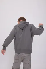 Hoodie gris de manga larga con capucha, corte holgado y bolsillo canguro.