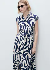 Vestido camisero midi con estampado abstracto en tonos azul y blanco. Tiene cuello camisero, cierre frontal con botones, cinturón desmontable y corte sin mangas.