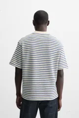 Polo de hombre con corte relaxed fit, cuello solapa con cierre frontal de botonadura y manga corta. Diseño a rayas horizontales en color crema y azul marino.