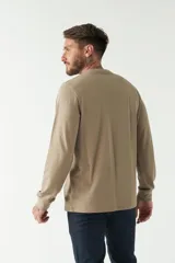 Remera color marrón de manga larga, con bolsillo en el pecho y logo de la marca en etiqueta sobre el bolsillo.