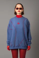 Buzo azul con costuras rojas a contraste y logo bordado en el pecho.
