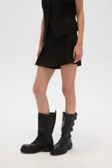 Minifalda negra con corte asimétrico y detalle de tabla en el frente.