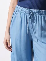 Pantalón de lyocell celeste, de corte ancho, con pretina elastizada con lazo de ajuste, bolsillos laterales y bolsillos cargo.