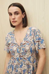 Vestido largo color verde oliva con estampado de hojas rosas, escote en V, botones al frente, mangas cortas y falda con leve vuelo.