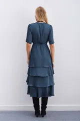 Vestido azul petróleo con escote en V, largo midi, mangas cortas, elástico en la cintura y falda con volados en capas.