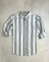 Camisa de hombre de algodón con apariencia similar al lino, a rayas verticales anchas en tonos gris y blanco, con cuello mao, manga larga con puños y cierre frontal con botones.