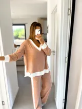 Conjunto de buzo y pantalón de morley beige con detalles en crudo. El buzo es de corte amplio con cuello en V y puños blancos. El pantalón es de corte recto con una franja blanca lateral.