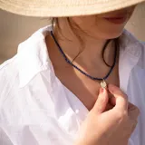 Collar corto con cuentas facetadas de lapislázuli azul y dije dorado con forma de luna y estrellas con incrustaciones de circonitas. El cierre y la cadena son de acero hipoalergénico con baño dorado. El collar finaliza con una perla de río.