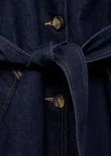 Abrigo largo de denim azul oscuro con cuello de solapa, cierre frontal con botones, dos bolsillos laterales, cinturón tipo batín y mangas largas.