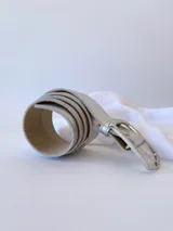 Cinto plateado de cuero con hebilla rectangular plateada.