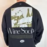 Buzo color crema con estampado de botellas de vino y texto en la espalda, corte oversize.