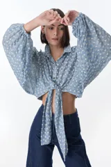 Camisa marrón con estampado de flores blancas, de corte cropped con nudo frontal y mangas largas abullonadas.