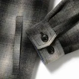 Campera a cuadros gris y negro con cuello de pana negro, cierre con botones y bolsillos frontales con solapa.