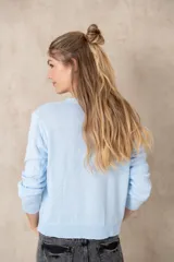 Cardigan celeste de tejido de punto, con cuello redondo y cierre frontal con botones.