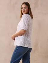 Blusa blanca labrada con cuello a la base, abertura central con botones y mangas cortas. Marca Sabrina Lauren.