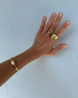 Brazalete rígido abierto de bronce con textura irregular.