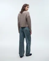 Pantalón jean cargo azul de silueta amplia, tiro medio y largo hasta el talón. Cuenta con cierre y botón metálico níquel en la cintura, bolsillos plaqué con cierres sobre las rodillas, bolsillos en costuras laterales y bolsillos ojal con labio en la espalda. Las tiras de ajuste con botones metálicos níquel en la botamanga aportan un toque funcional.