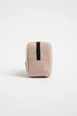 Necesser rectangular color beige con cierre superior negro, asa lateral y parche con logo de estrella.