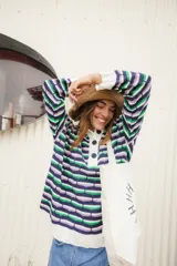Sweater oversize de punto con rayas horizontales en colores azul, verde y lila. Tiene cuello polo blanco con cartera de botones.