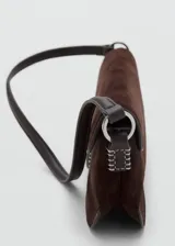 Bolso de hombro rectangular de piel de serraje color marrón oscuro, con solapa curva y cierre metálico central. Presenta costuras decorativas blancas en los laterales y una correa fina de hombro.