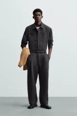 Sobrecamisa negra de corte amplio, con cuello solapa, manga larga con puños abotonados, bolsillos de parche en el pecho, bolsillos laterales y cierre frontal con botones.