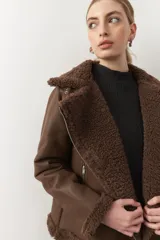 Campera de símil cuero color tierra, con forro de corderito, bolsillos con cierre metálico y hebilla en el cuello.