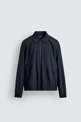 Cazadora bomber color azul marino de tejido técnico ligero, con cuello solapa y manga larga. Cuenta con bolsillos de vivo en la cadera, bolsillo interior, acabados en rib y cierre frontal con cremallera.