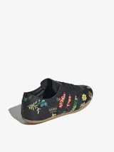 Zapatillas Adidas modelo Tokyo, color negro con bordados florales multicolores. Diseño de corte bajo con las tres tiras laterales y suela de goma color caramelo.