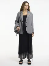 Blazer a cuadros blanco y negro con botones y solapa en la parte delantera. Tiene apliques de pines y bolsillos con solapa.