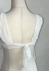 Top blanco de microtul con breteles finos y corte asimétrico.