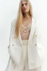 Blazer blanco de doble botonadura con solapas de muesca, hombreras y bolsillos delanteros ribeteados con solapa.