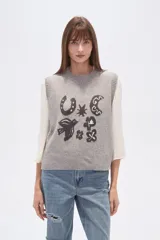 Chaleco de punto sin mangas confeccionado en rayón con efecto confetti en color gris melange. Presenta un diseño frontal en jacquard con diversos motivos como una herradura, una luna, un pájaro y estrellas, con cuello redondo y terminaciones acanaladas.