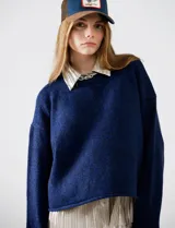 Buzo de tejido melange azul oscuro, con cuello redondo y mangas largas, corte cropped y calce holgado.