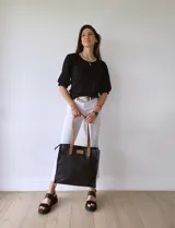 Bolso tipo tote bag de cuero negro con forro de tela, doble asa de cuero color suela, bolsillo frontal y bolsillo interno.