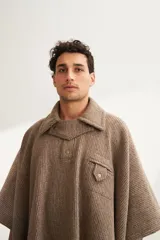 Poncho unisex de lana fina color marrón claro, con cuello polo, cartera con broches a presión y bolsillo ojal.