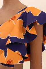 Top de bikini asimétrico con estampado floral en tonos naranja y azul, con un solo hombro y volado grande.