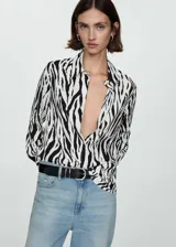 Camisa de manga larga con estampado de cebra en blanco y negro, cuello camisero y cierre frontal con botones.
