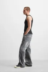 Pantalón de jean gris de corte flare, con cinco bolsillos, lavado con efecto de contraste en las piernas y bajo con acabado irregular.
